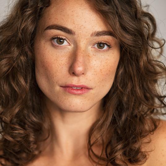 Portrait of a woman with curly hair and natural freckles
